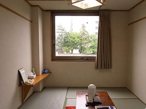 Cette chambre dispose d'une grande fenêtre et d'une table. dans l'établissement Hotel Fukui Castle - Vacation STAY 58699v, à Fukui