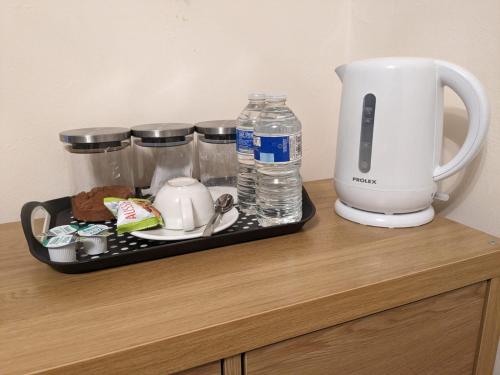 ein Tablett mit einer Kaffeemaschine und Wasserflaschen auf der Theke in der Unterkunft Large Cosy Room to Stay in South Reading in Shinfield