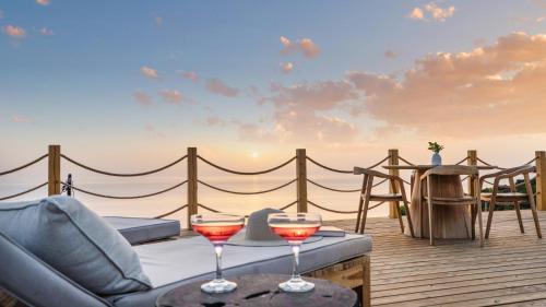 a patio with a couch and two glasses of wine at Eunoia Porto Katsiki in Áyios Nikólaos Nirás