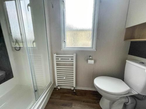 a bathroom with a toilet and a window at Lovely 6 Berth Caravan At Caldecott Hall Country Park, Norfolk Ref 91010c in Great Yarmouth