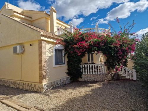una casa amarilla con flores a un lado. en Relaxing 3 bed 3 bath Villa for 8 Camposol Sect D, en Mazarrón