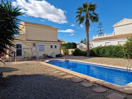 una piscina frente a una casa con palmeras en Relaxing 3 bed 3 bath Villa for 8 Camposol Sect D, en Mazarrón