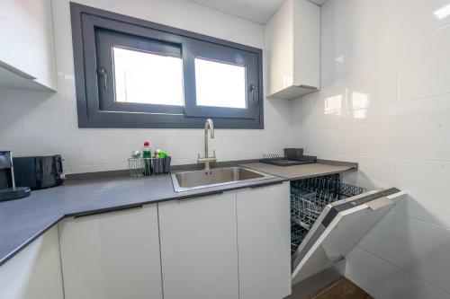 biała kuchnia ze zlewem i oknem w obiekcie ApartamentosDnord w mieście Reus