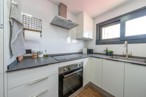 cocina con armarios blancos, fregadero y ventana en ApartamentosDnord en Reus