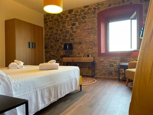 a room with a bed and a window and a table at Orizzonti Toscani new apartment with view and pool in Laiatico