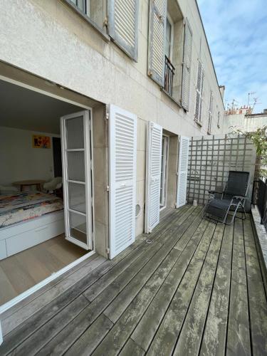 una terrazza in legno con una sedia sul lato di un edificio di Superbe studio avec balcon, situé entre 6è et 7è ! a Parigi