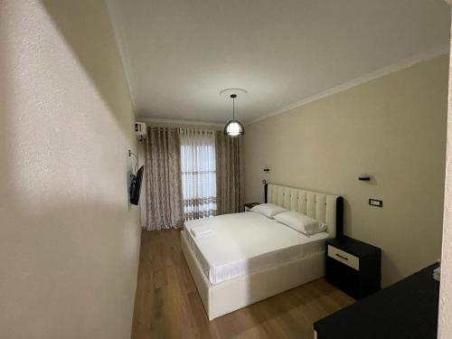 1 dormitorio con cama blanca y ventana en Hotel Belvedere, en Pogradec