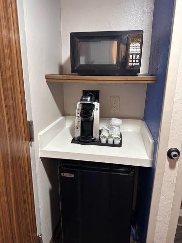 a kitchen with a microwave and a coffee maker on a shelf at Holiday Inn Express Hotel and Suites Mesquite by IHG in Mesquite