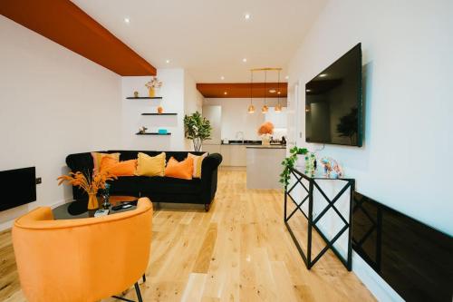 a living room with a black couch and a kitchen at Dawn House - Wyndale Living -Bham JQ 3BR Townhouse in Birmingham