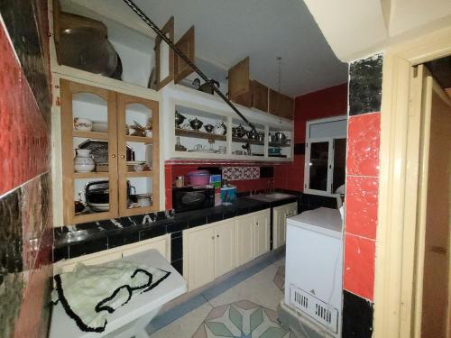 a kitchen with white cabinets and a red wall at khenifra in Khenifra