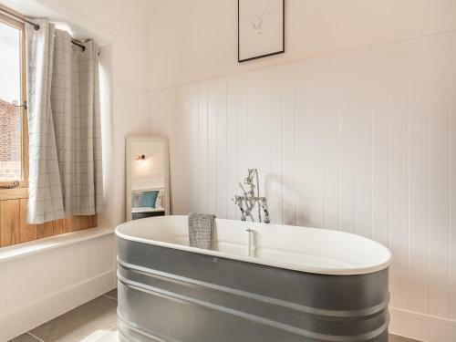 La salle de bains est pourvue d'une baignoire et de murs blancs. dans l'établissement The Red Rooster - Uk44440, à Arlingham