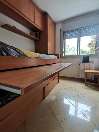 1 dormitorio con banco de madera en una habitación en Habitación acogedora a 20min del centro, en Barcelona, en Santa Coloma de Gramenet