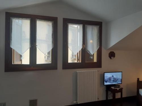 two windows with white curtains in a room at Monolocale piano alto luminoso pochi minuti metro rossa Milano in Milan