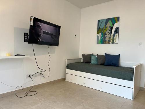 a bedroom with a bed with a flat screen tv on the wall at Depto 1 dormitorio vista al mar!! in Puerto Madryn