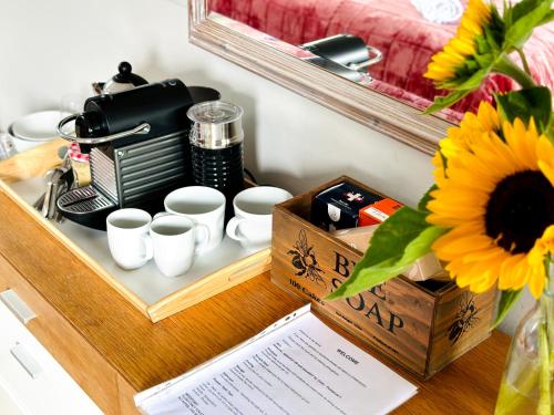 une table avec des tasses, une cafetière et un tournesol dans l'établissement Heathers loft space, à Londres