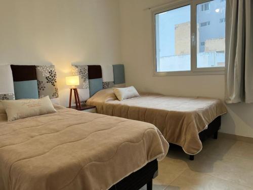 two beds in a room with a window at Depto 1 dormitorio vista al mar!! in Puerto Madryn