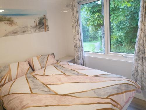 een bed in een slaapkamer met een raam bij Wood View - Penstowe Park in Kilkhampton