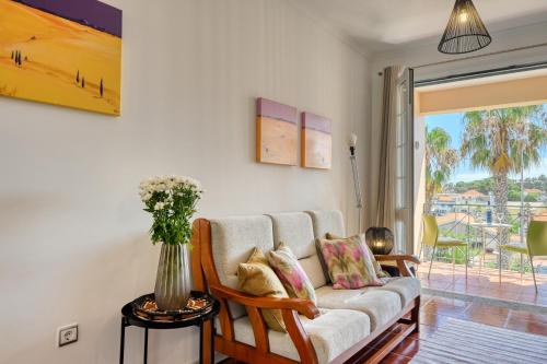 ein Wohnzimmer mit einem Sofa und einer Vase aus Blumen in der Unterkunft Porto Santo Pip House, a Home in Madeira in Porto Santo