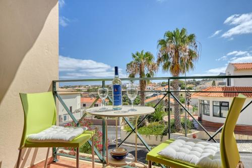 a balcony with a table and chairs and palm trees at Porto Santo Pip House, a Home in Madeira in Porto Santo