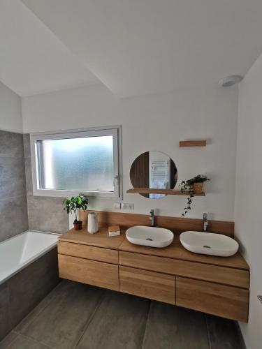 une salle de bain avec deux lavabos, une baignoire et un miroir dans l'établissement Villa des Oyats, à Vieux-Boucau-les-Bains