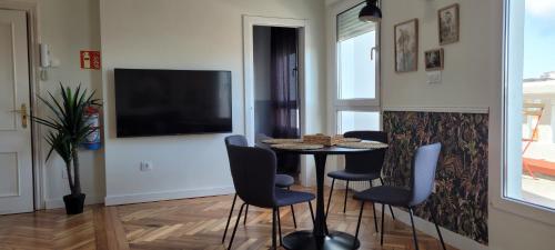 a dining room with a table and chairs and a television at SUITE HAUS Catedral in Santander