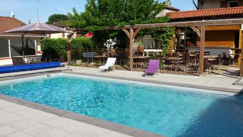 a swimming pool with two chairs and a table at Logis Cruzel in Maurs