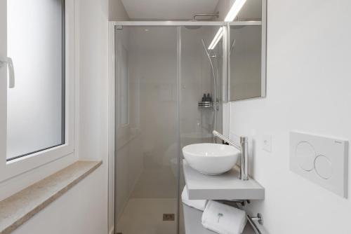 a white bathroom with a sink and a shower at Living Ascona Boutique Hotel in Ascona