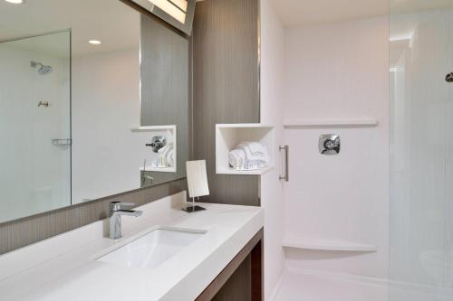 Baño blanco con lavabo y espejo en Courtyard Charlotte Steele Creek en Charlotte