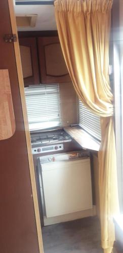 Il comprend une petite cuisine avec une cuisinière et une fenêtre. dans l'établissement coté plage caravane front de mer, à Vias