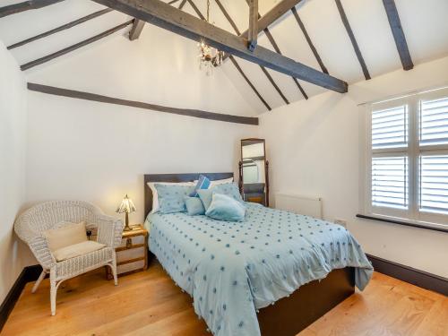 a bedroom with a bed and a chair and a window at Cutters Cottage in Roydon