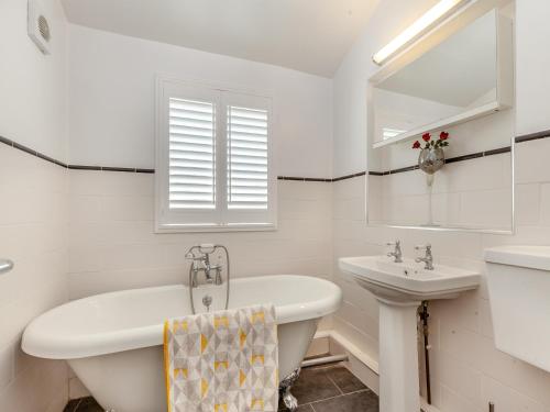 a white bathroom with a tub and a sink at Cutters Cottage in Roydon