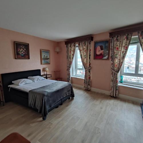 une chambre avec un grand lit et deux fenêtres dans l'établissement Les Goélands maison avec vue sur port et falaise, à Fécamp