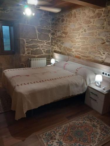 a bedroom with a bed and a stone wall at Casa de Crabera in Dodro