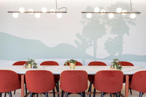 a conference room with a table and red chairs at Living Ascona Boutique Hotel in Ascona