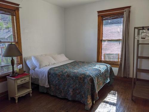 a bedroom with a bed and a lamp and two windows at The Oliver House - Adults Only in Bisbee