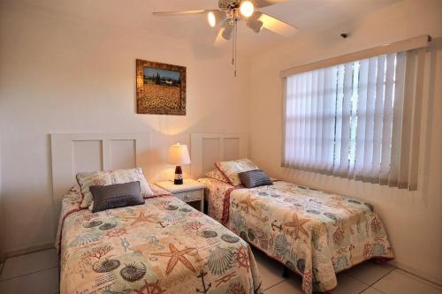 a bedroom with two beds and a lamp and a window at 2306 Ocean Pointe in Tavernier