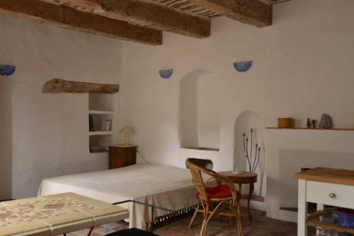 1 dormitorio con 1 cama, mesa y sillas en Studio de la cheminée et studio de la place en Sigonce