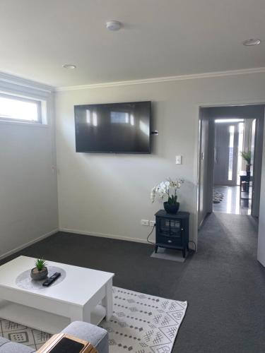 a living room with a couch and a tv on the wall at Bunker on Belt in New Plymouth