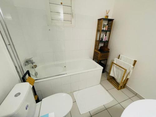 ein Badezimmer mit einer weißen Badewanne und einem WC in der Unterkunft Bel appartement cosy - Les pieds dans l'eau in Le Gosier