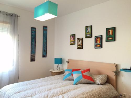a bedroom with a bed and pictures on the wall at Maré Cheia in Tavira