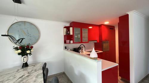 a kitchen with red cabinets and a counter with a table at Villetta Moderna accanto al Centro di Lugano in Agno