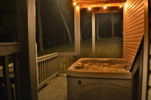 a bath tub sitting on a porch at night at In The Woods - 5 BR Chalet with Game Room, Fire Table and Hot Tub in McGaheysville