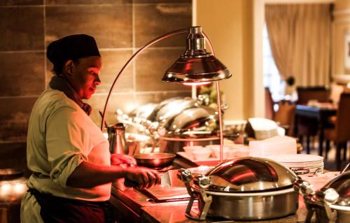a woman standing in a kitchen preparing food at Southern Sun Bloemfontein in Bloemfontein