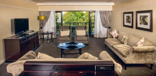 a living room with a couch and a tv at Southern Sun Bloemfontein in Bloemfontein