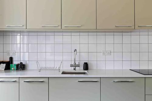 a kitchen with white cabinets and a sink at Modern 3 Bed Apartment in Tottenham in London