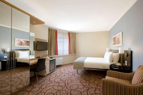 um quarto de hotel com uma cama, uma secretária e uma cadeira em SunSquare Cape Town Gardens em Cidade do Cabo