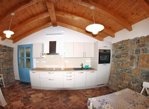 - une cuisine avec des placards blancs et un mur en pierre dans l'établissement Pr' Marici, à Koper
