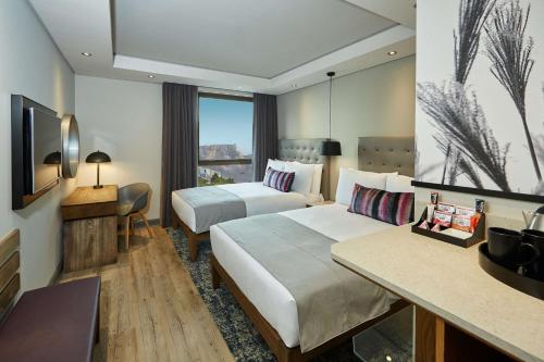 a hotel room with two beds and a television at SunSquare Cape Town City Bowl in Cape Town