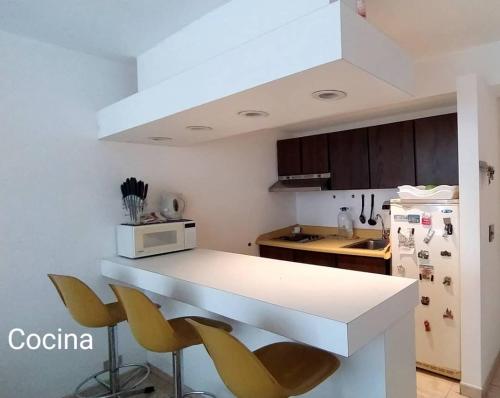 a kitchen with a white counter and yellow chairs at Contemporary in Caracas