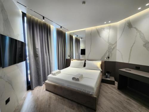 a bedroom with a white bed and a television at Charm Hotel in Vlorë